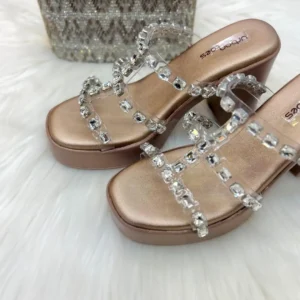 Elevate your festive look with our Cinderella Crystal Platform Wedges. Featuring trendy transparent straps encrusted with shimmering baguette crystals and a luxurious rose-gold metallic base, these platforms offer high-octane glamour without compromising on stability. Perfect for the modern bridesmaid or a night out.